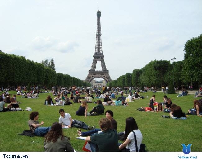 Ngồi thư giãn trên bãi cỏ gần tháp Eiffel ở Paris